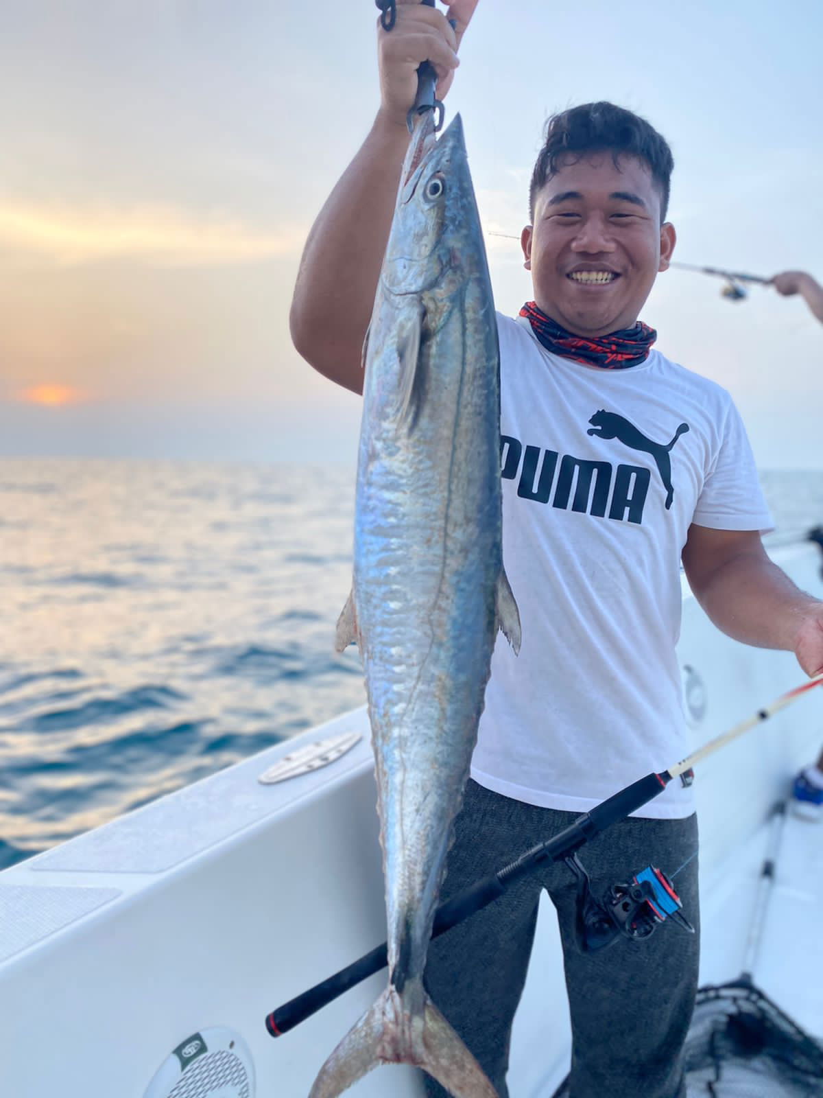 Fisherman holding trophy fish at sunset during deep sea fishing in Dubai