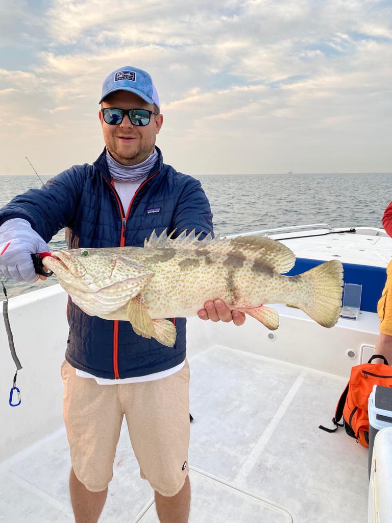 Tourist proudly holding kingfish on deep sea fishing boat in Dubai