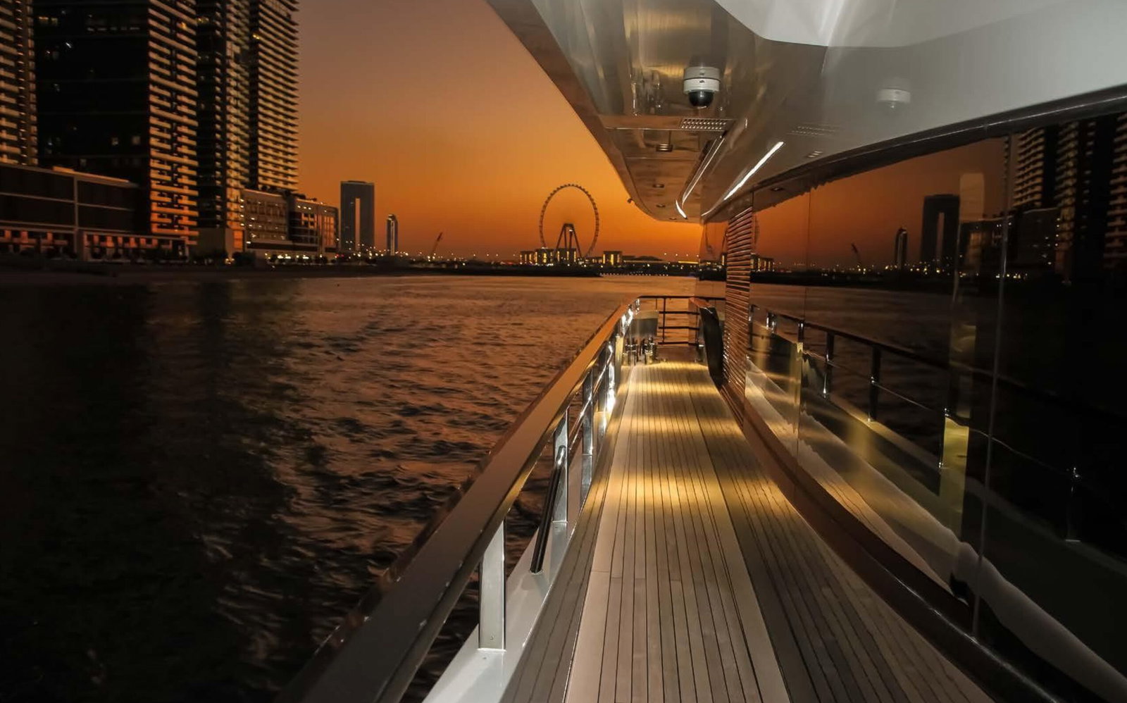 Saffuriya VIP yacht deck at sunset with city skyline views, warm golden light and teak walkway
