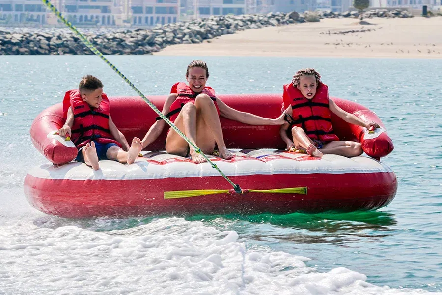 Family enjoying a donut ride on an inflatable water tube wearing life jackets in Dubai