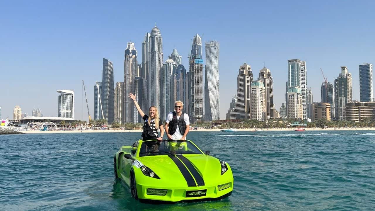 Couple enjoying green jet car ride in Dubai Marina with skyscraper skyline background